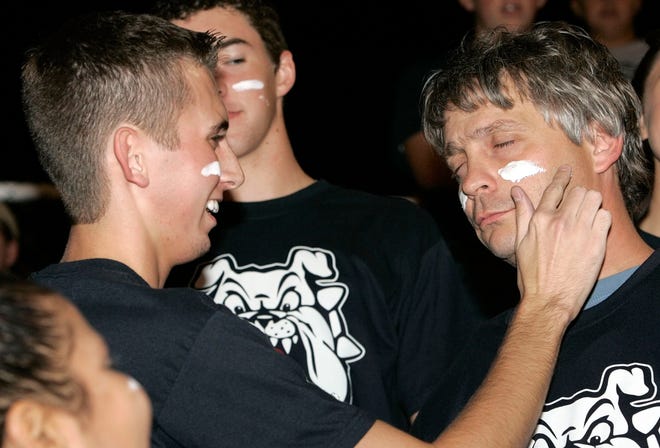 The Oklahoman's Berry Tramel, right, has paint applied to his face by Hunter Scott with the Dog Squad, Minco's student cheering section, during a high school football game against Wewoka in 2006.