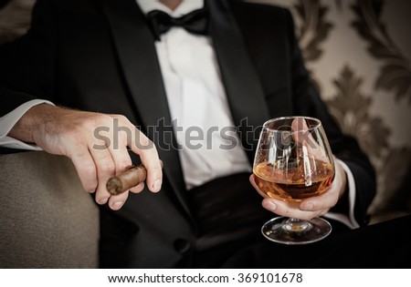 stock-photo-gentleman-holding-glass-of-cognac-and-cigar-369101678.jpg